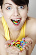 Woman with handful and mouthful of candies.