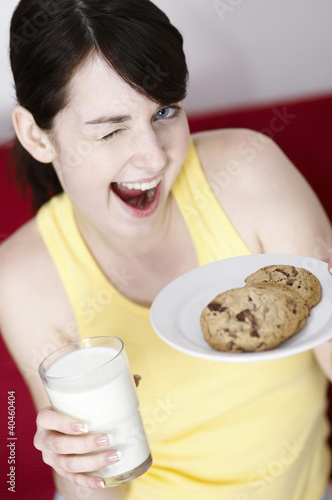 Photo: Woman holding cookies and a glass of milk. Woman holding cookies and a glass of milk.