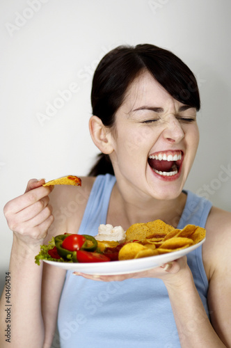 Photo: Woman eating chips. Woman eating chips.