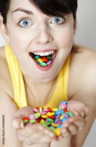 Photo: Woman with handful and mouthful of candies. Woman with handful and mouthful of candies.