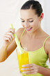 Woman dipping celery stalk into a glass of orange juice.