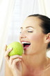 Woman biting on a green apple.