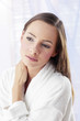 Woman in bathrobe staring blankly at a space.