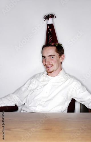 Photo: Businessman with party hat smiling at the camera. Businessman with party hat smiling at the camera.