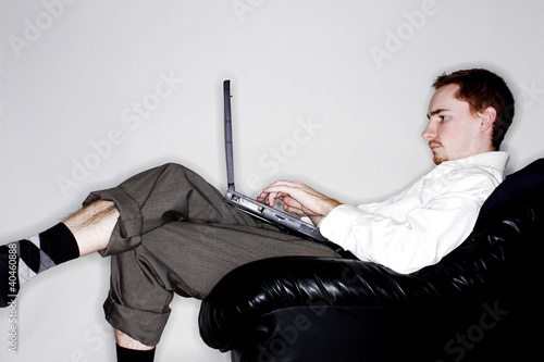 Photo: Businessman sitting on the couch using laptop. Businessman sitting on the couch using laptop.