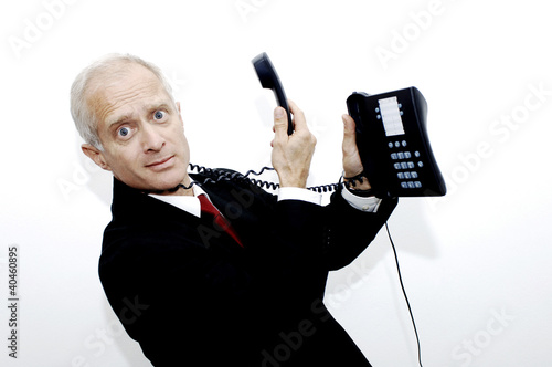 Photo: Phone cord entangling around businessman's neck. Phone cord entangling around businessman's neck.