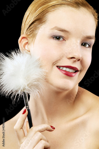 Photo: Woman tickling her face with white fur. Woman tickling her face with white fur.