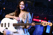 Young guitar player performing in night club