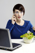 Photo: Woman eating salad while talking on the handphone. Woman eating salad while talking on the handphone.