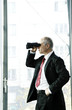 Photo: Businessman using binoculars. Businessman using binoculars.