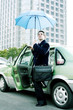 Photo: Businessman holding an umbrella while getting out from taxi. Businessman holding an umbrella while getting out from taxi.