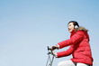 Foto: Woman listening to music while cycling. Woman listening to music while cycling.