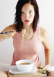 Woman eating a bowl of noodles.