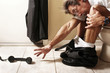 Businessman sitting on the toilet bowl trying to reach for the telephone.