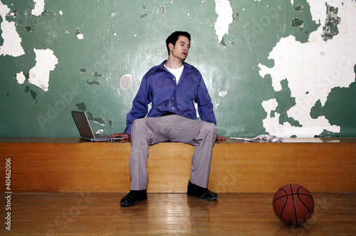 Photo: Businessman sitting in a basketball court. Businessman sitting in a basketball court.