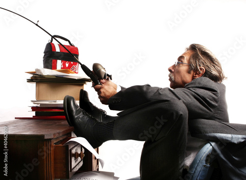 Photo: Businessman fishing at his table. Businessman fishing at his table.