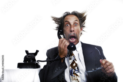 Photo: Businessman receiving a shocking phone call. Businessman receiving a shocking phone call.