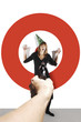 Photo: Hand aiming a pistol at a businesswoman with party hat. Hand aiming a pistol at a businesswoman with party hat.