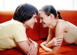 Couple lying on the couch facing each other.