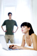 Man watching his wife using laptop.