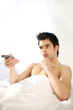 Man channel surfing on the bed.