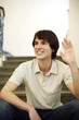 Man sitting on the staircase waving his hand.