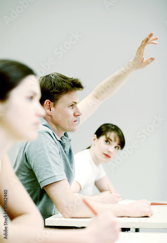 Foto: Man raising his hand to answer question. Man raising his hand to answer question.
