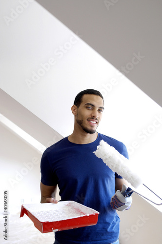 Photo: Man holding a paint roller and a paint tray. Man holding a paint roller and a paint tray.