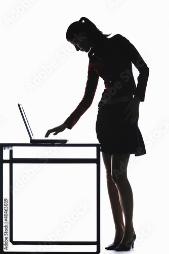 Photo: Silhouette of businesswoman using laptop. Silhouette of businesswoman using laptop.