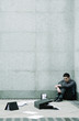Depressed businessman sitting at the corner of a building.