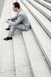 Photo: Businessman sitting on the stairs thinking. Businessman sitting on the stairs thinking.