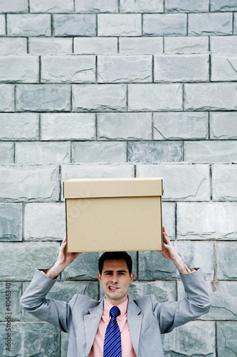 Photo: Businessman carrying a box on his head. Businessman carrying a box on his head.