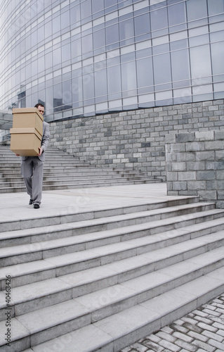 Photo: Businessman carrying a stack of boxes down the stairs. Businessman carrying a stack of boxes down the stairs.