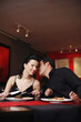 Man whispering into his girlfriend's ear while having dinner in a restaurant