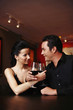Couple locking arms, holding glass of wine