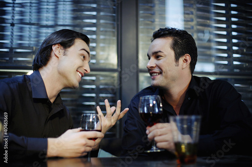 Photo: Man talking to his friend while drinking in a bar Man talking to his friend while drinking in a bar