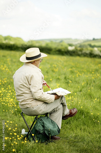 Photo: Senior man sitting on the chair drawing Senior man sitting on the chair drawing