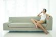 Woman sitting on the couch listening to music on the headphones