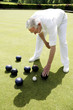 Man bending down to pick up bowling balls