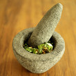 Basil, pine nuts and Parmesan cheese in a pestle and mortar for making pesto sauce.