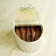 Tin of anchovies on rough marble with lid peeled back