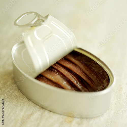 Foto: Tin of anchovies on rough marble with lid peeled back Tin of anchovies on rough marble with lid peeled back