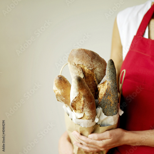 Photo: Woman holding a selection of fresh Italian rustic bread, one with poppy seeds Woman holding a selection of fresh Italian rustic bread, one with poppy seeds