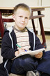 Boy looking at the camera while holding a pen and a book