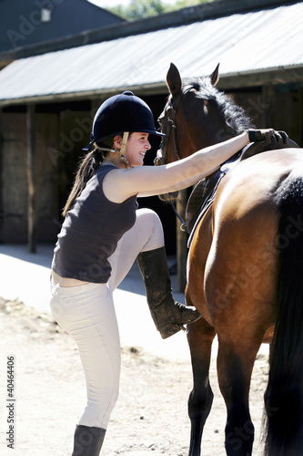Photo: Woman trying to get on a horse Woman trying to get on a horse