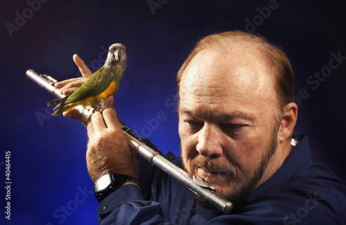 Photo: Man playing flute with bird on it Man playing flute with bird on it