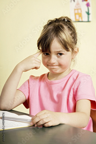 Photo: Girl thinking while sitting at her table Girl thinking while sitting at her table