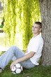 Foto: Young man sitting under a tree Young man sitting under a tree