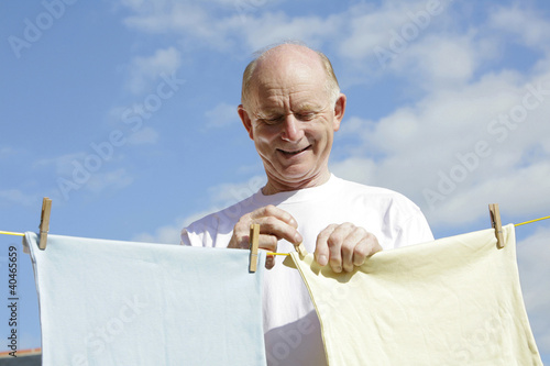 Photo: Senior man hanging clothes on the clothesline Senior man hanging clothes on the clothesline