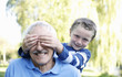 Boy covering his grandfather's eyes
